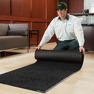 UniFirst Route Service Rep delivers a clean mat to a business and rolls it out in place