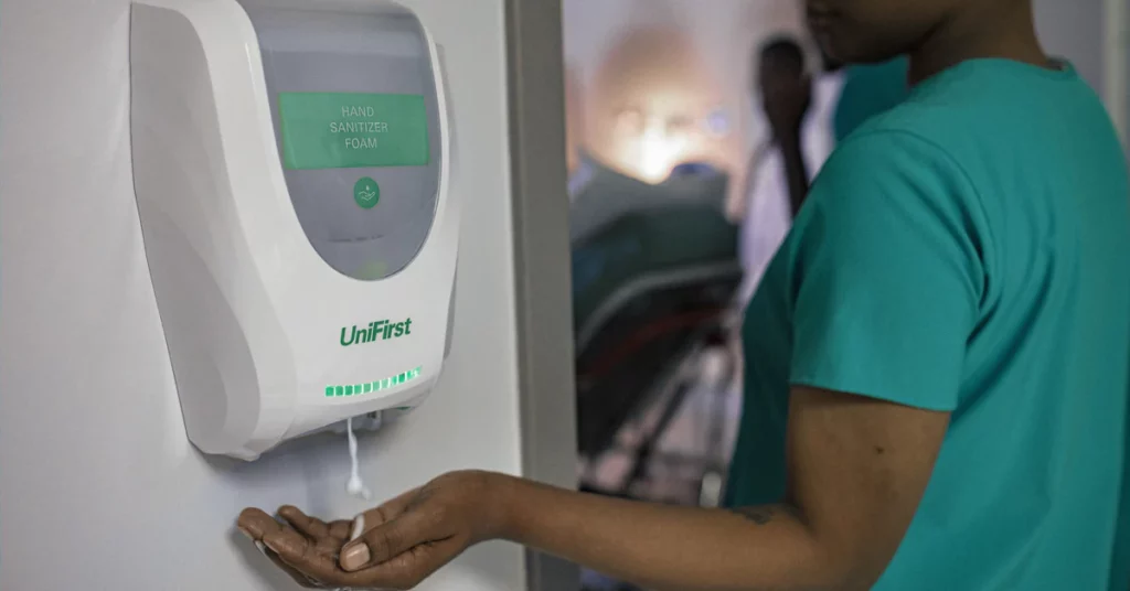 Healthcare professional uses a UniFirst dispenser for hand sanitizing foam.