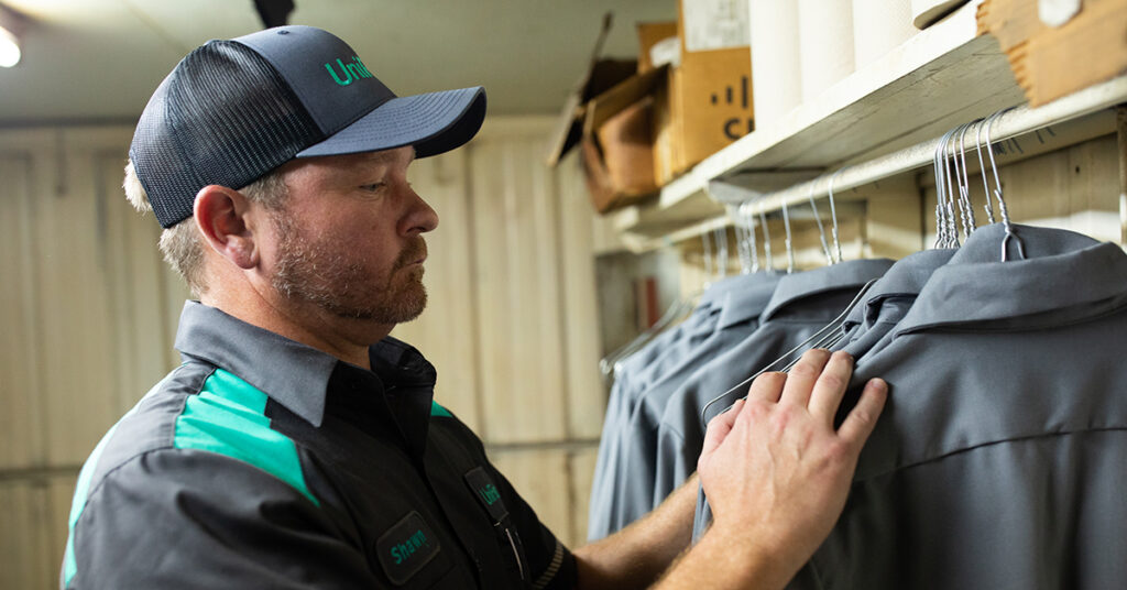 UniFirst Route Sales Representative delivers a group of uniform shirts to a business location.