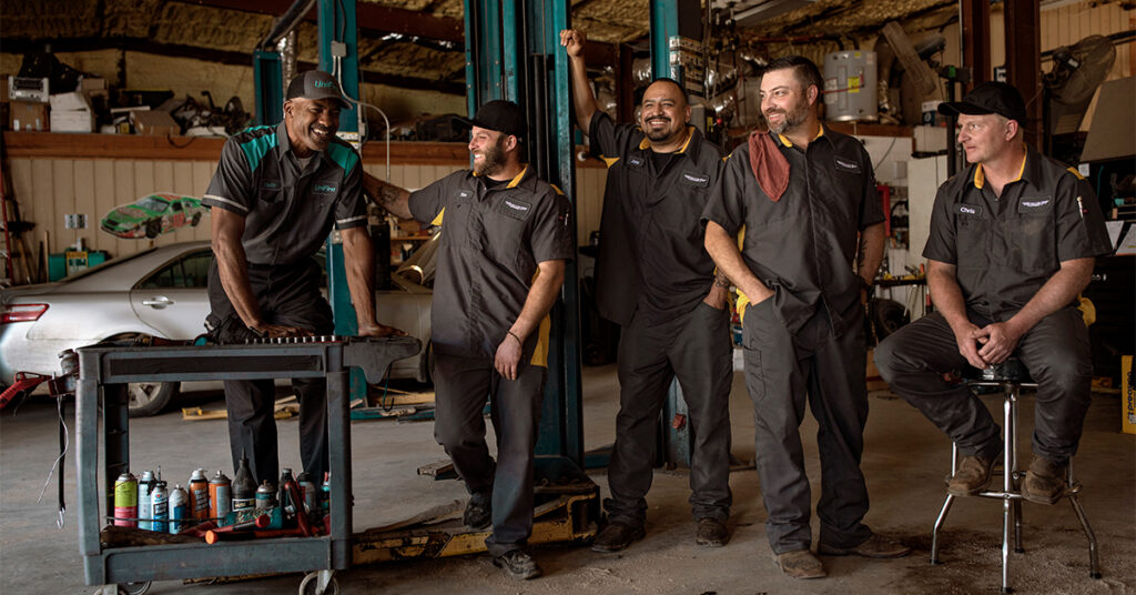 UniFirst RSR standing and laughing with uniformed automotive workers.
