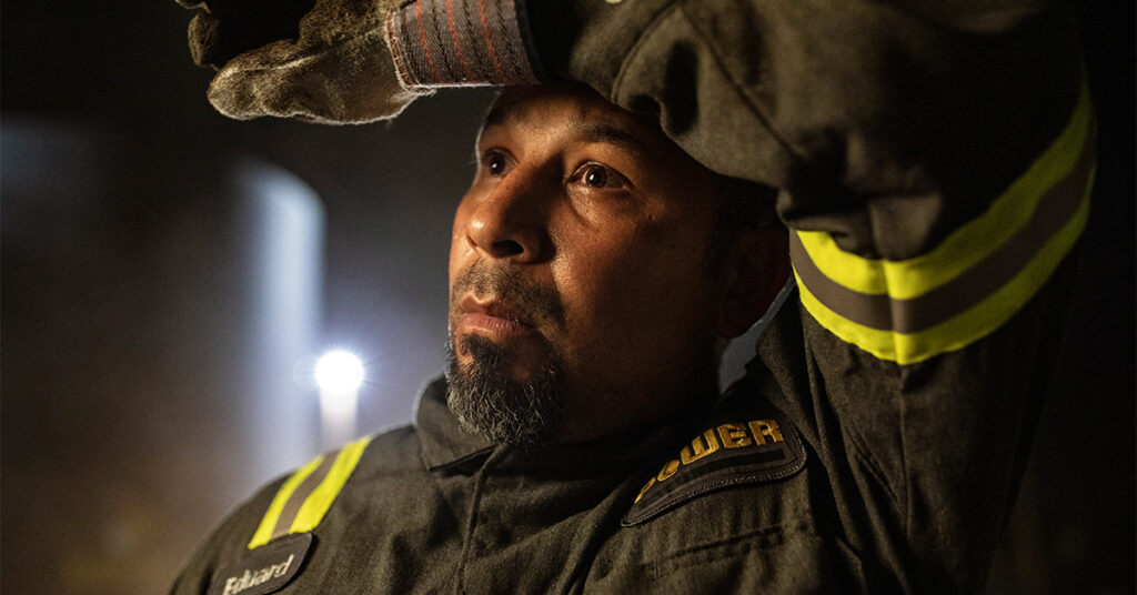 Uniformed energy worker wipes forehead after the work day.