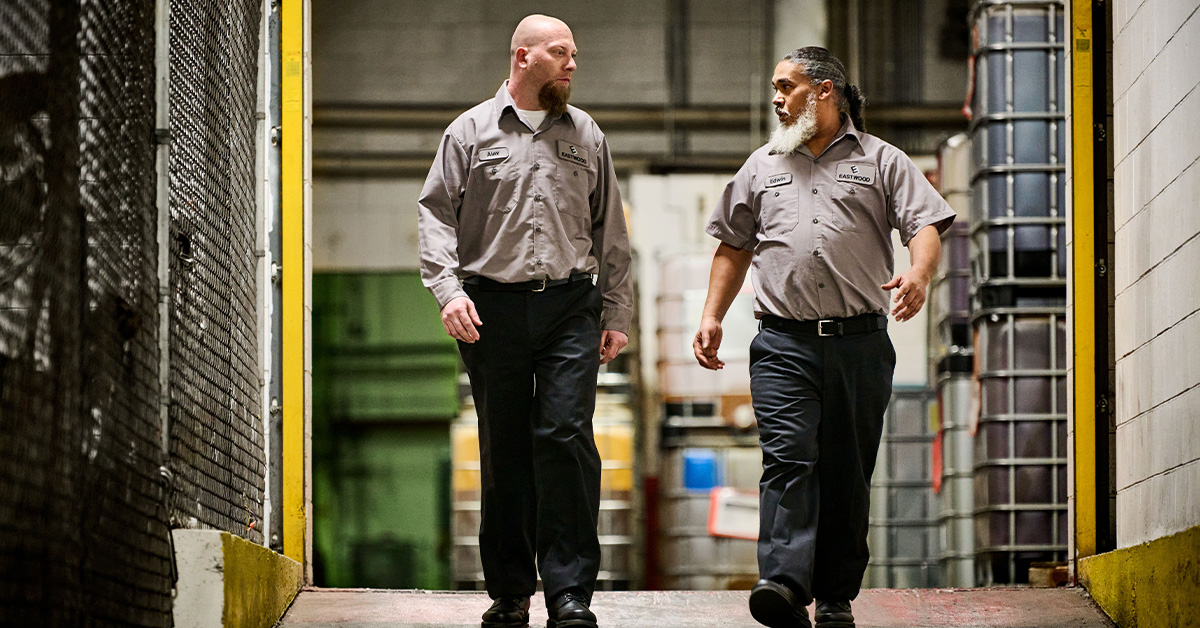 Automotive manufacturing workers walking down ramp wearing UniFirst uniform pants and shirts.