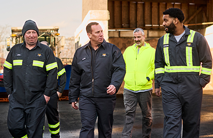 A group of workers in enhanced visibility UniFirst workwear walking through a lot together