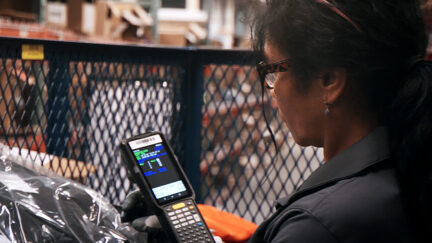 UniFirst Team Partner scanning product at a UniFirst location and how tariffs could impact uniform costs