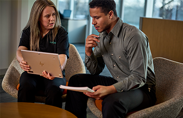 A UniFirst representative sits with a uniform customer discussing uniform rental service