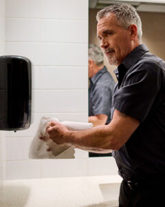 Man drying hands with paper towels in a restroom