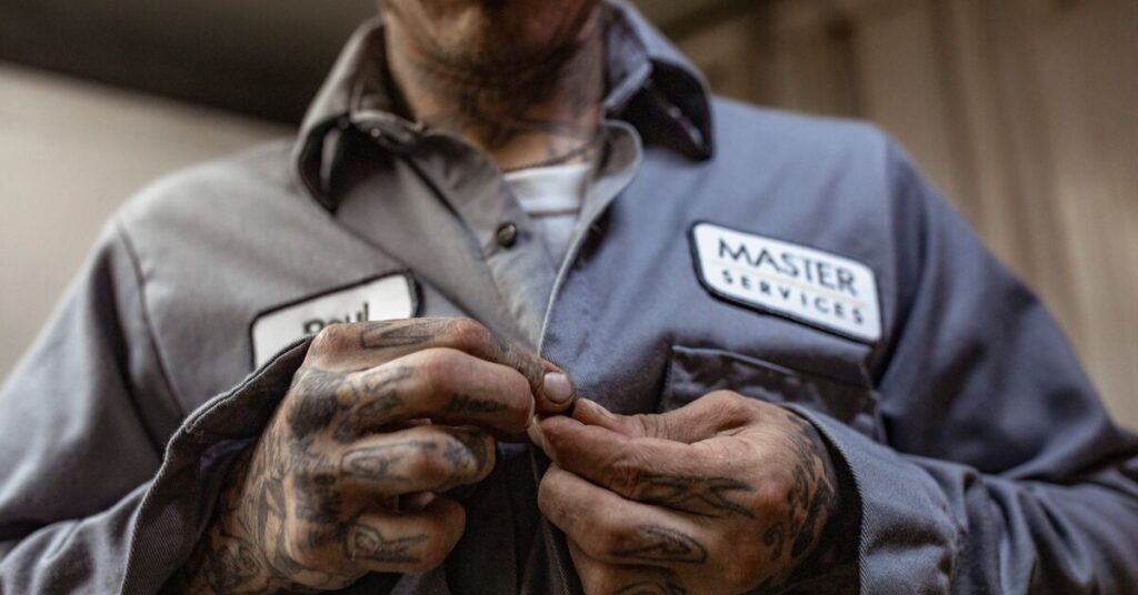 A man buttons up his industrial laundered uniform provided by UniFirst