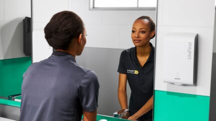 Women using dispenser washing her hands to promote good workplace hygiene