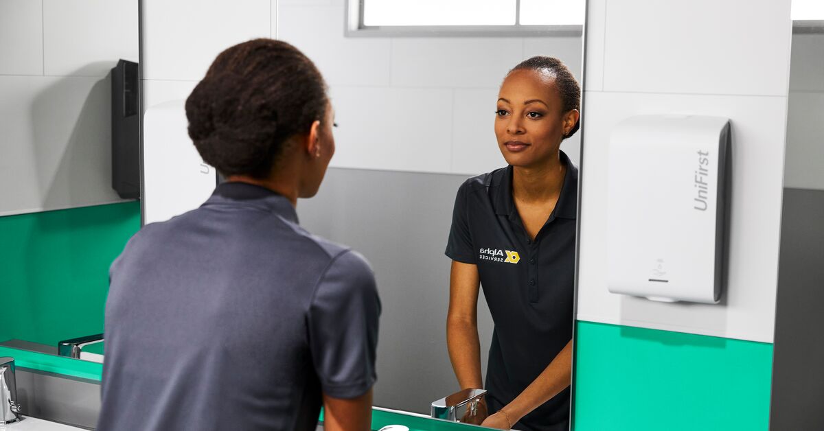 Women using dispenser washing her hands to promote good workplace hygiene