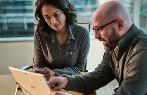 A UniFirst rep discussing procurement strategy with a customer at a table with a laptop