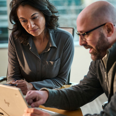 A UniFirst rep discussing procurement strategy with a customer at a table with a laptop