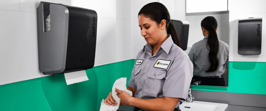 A UniFirst facility management customer uses a UniFirst restroom dispenser and paper towel