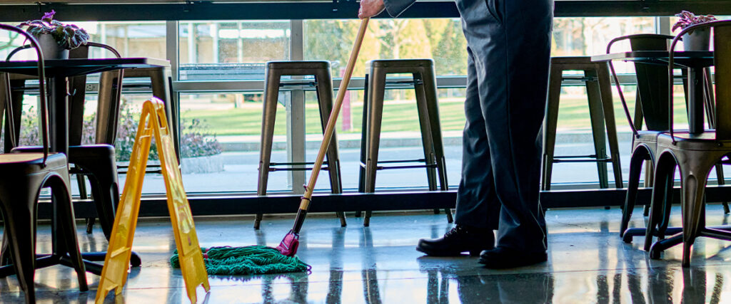 A worker mopping the floors in a public cafe as part of UniFirst managed inventory for facility services