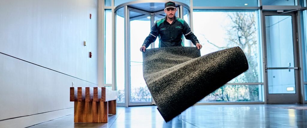 A UniFirst RSR replacing a mat at a customer location as part of facility management