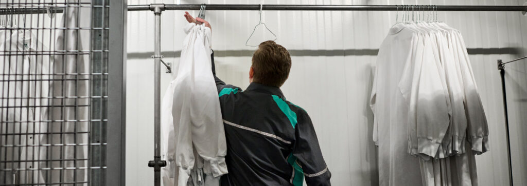 A UniFirst RSR hanging up work shirts at a customer location