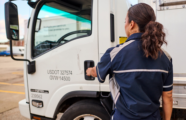 A women getting into a commercial truck cab while wearing her work uniforms