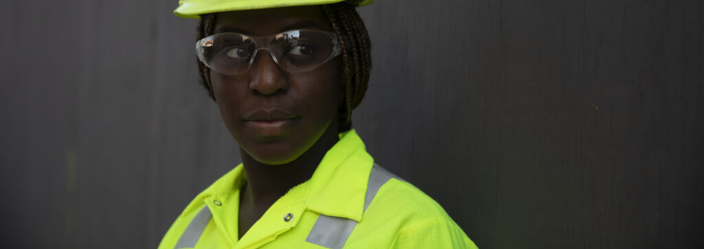 A woman standing in front of a dark background wearing safety apparel