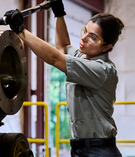A woman using tools to complete her job tasks while wearing stretch uniforms for comfort