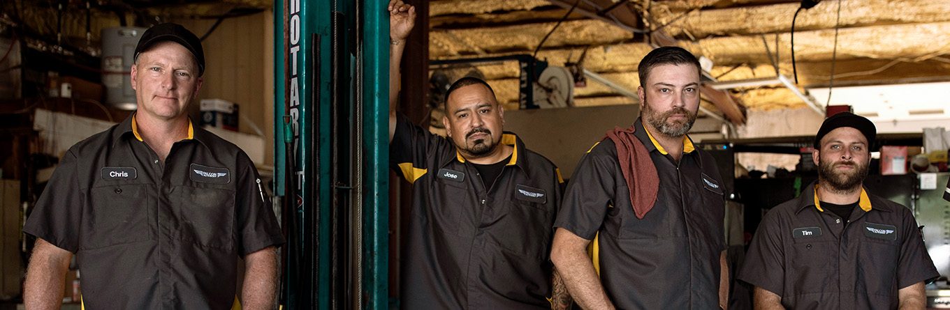 Four automotive mechanics take a break in the shade from a long and hot day of work while staying cool and comfortable wearing Mimix Workwear provided by UniFirst.